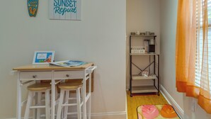 A room with a wooden desk, two stools, a coffee bar, and a bookshelf. - Gulf Breeze Vacation Rental for 2 w/ Pool Access! (Gulf Breeze)