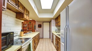 A kitchen with wooden cabinets, a microwave, stove, and a refrigerator. - Green Valley Abode w/ Pool Access & Mtn Views (Green Valley)