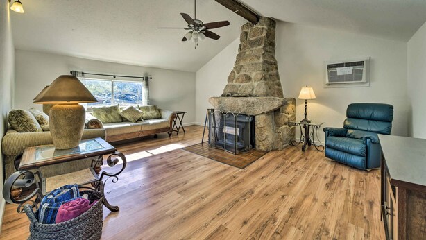 A cozy living room with a stone fireplace, a ceiling fan, and a comfortable seating area with a sofa and a chair. - Charming Miami Desert Escape w/ Yard + Patio! (Miami)