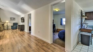 A spacious living area with hardwood flooring, a black leather chair, a small table with a lamp, and a television mounted on the wall. - Charming Miami Desert Escape w/ Yard + Patio! (Miami)