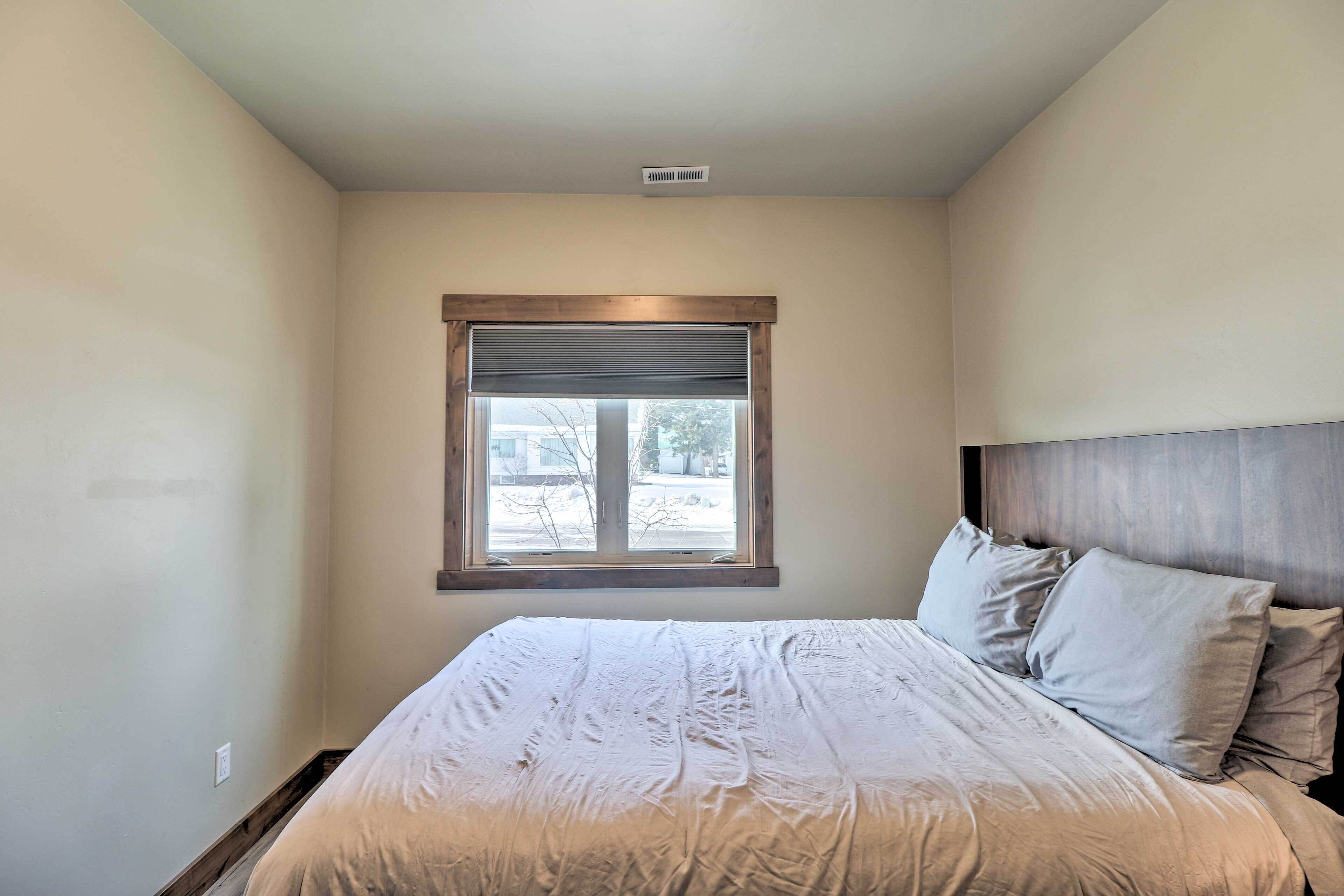 Une chambre à coucher avec un grand lit, une fenêtre avec des stores et une tête de lit.