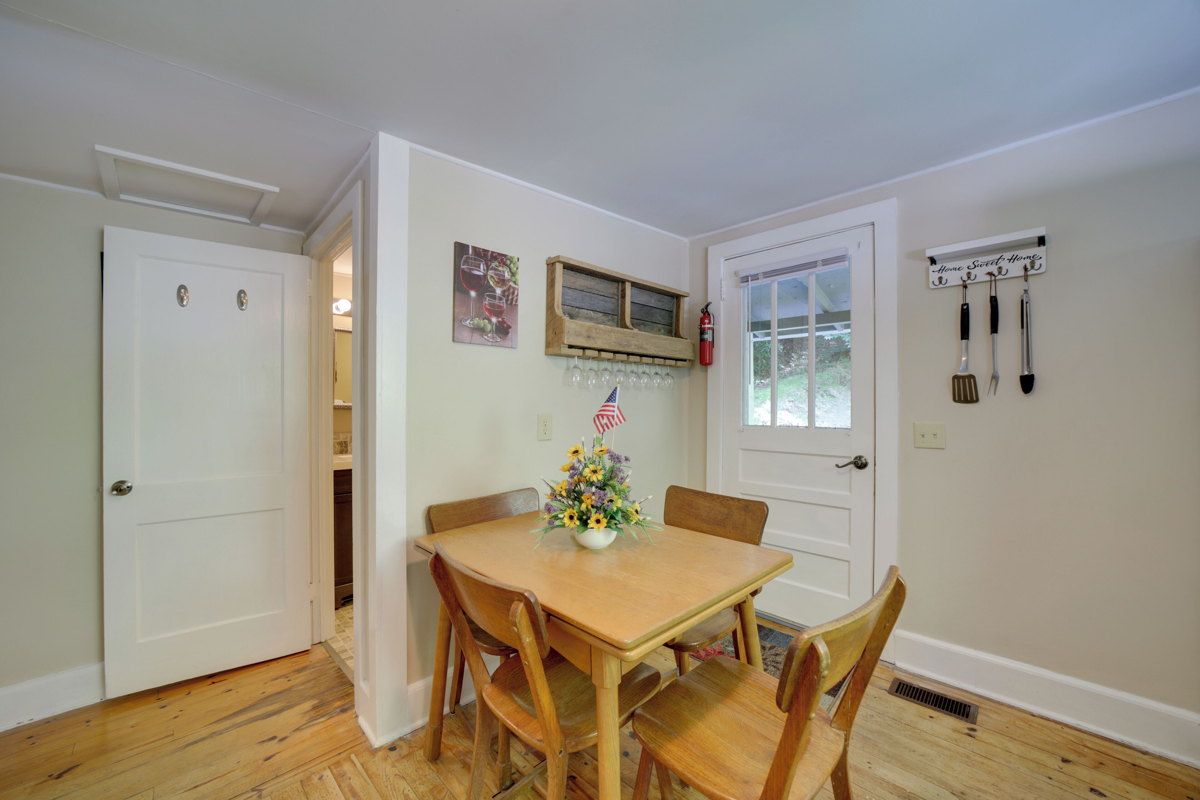 A dining area with a wooden table and chairs, a small American flag, and a wall-mounted utensil rack.