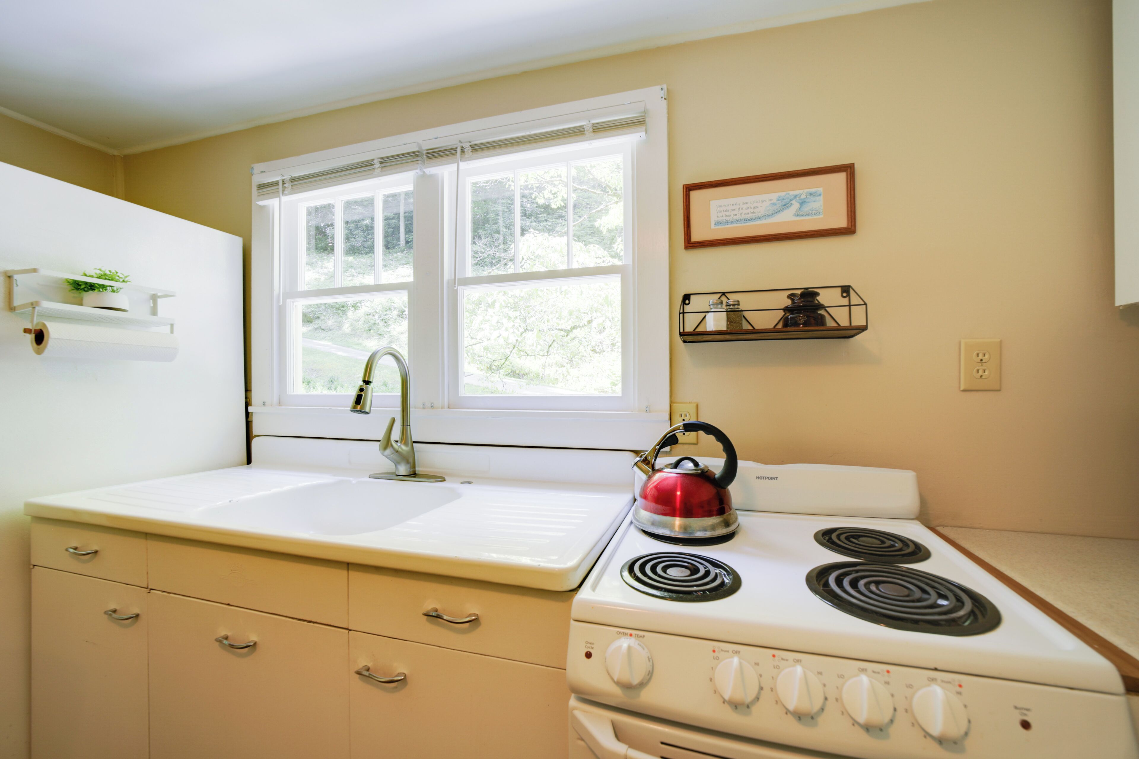 A kitchen with a double sink, stove, and window.
