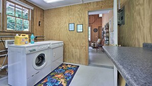Une buanderie équipée d’un lave-linge, d’un étendoir et d’une fenêtre avec des stores.