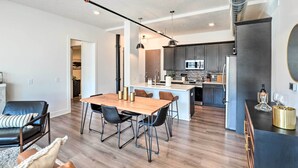 Een moderne keuken met donkere kastjes, een centraal eiland en een inbouwoven.