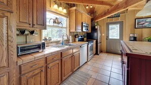 Una cocina con armarios de madera, microondas, refrigerador y lavamanos.