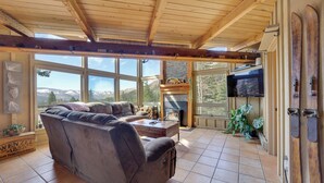 Una sala de estar acogedora con un amplio sofá modular, una chimenea y vistas a montañas.