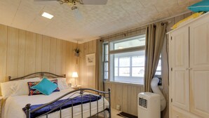 A bedroom with a bed, bedside table, lamp, window, and a white heater. - Scenic Home on the Delaware River, Pet-friendly! (Hancock)