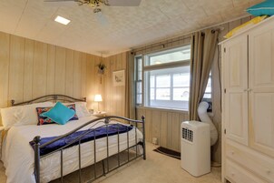 A bedroom with a bed, bedside table, lamp, window, and a white heater.