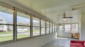 A covered porch with large windows, a ceiling fan, and a red sofa. - Scenic Home on the Delaware River, Pet-friendly! (Hancock)