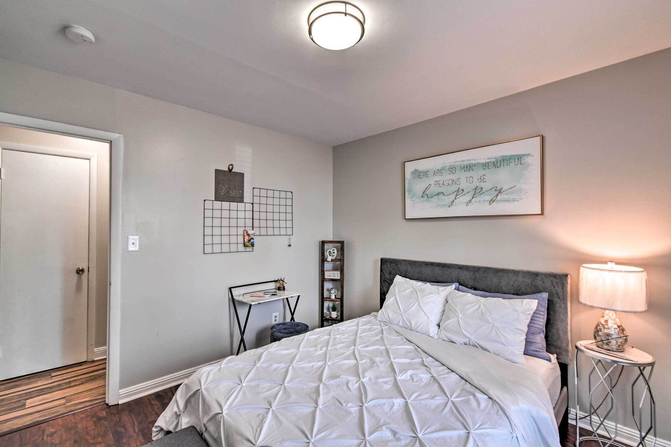 A bedroom with a bed, bedside table, lamp, and wall decor.