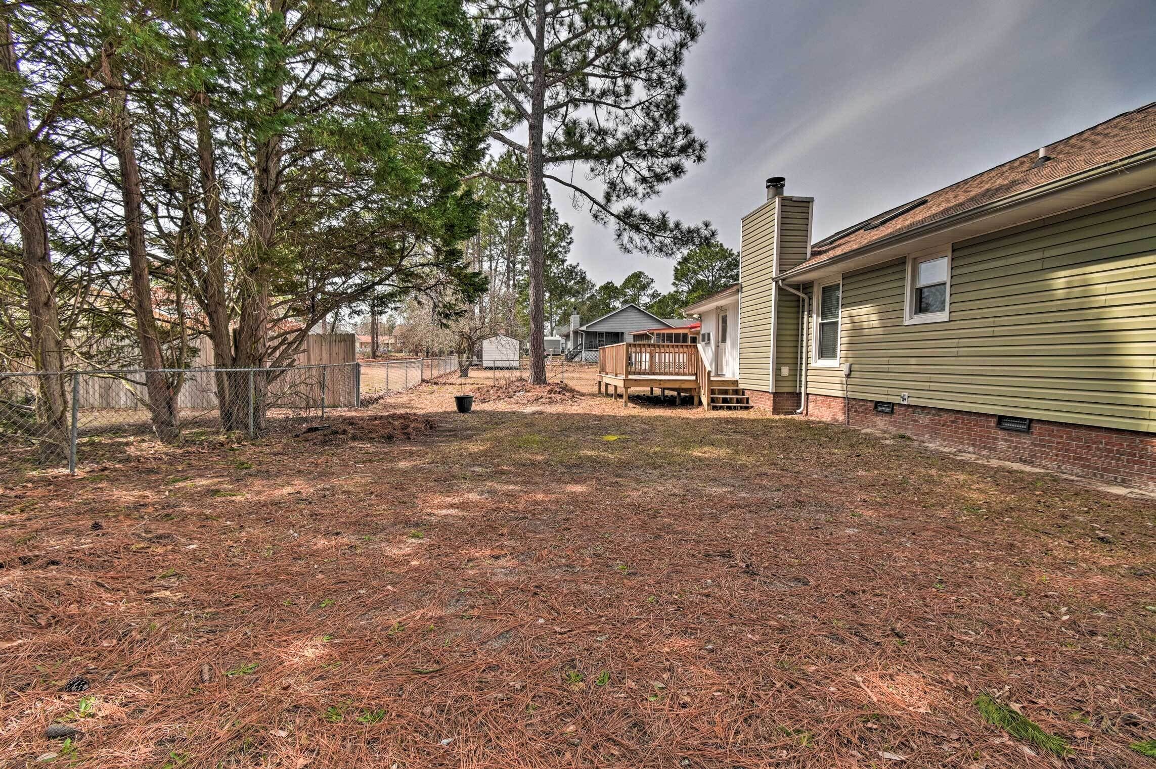 A residential property with a fenced yard, a wooden deck, and a house with a chimney.