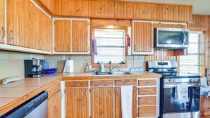 A kitchen with wooden cabinets, a microwave, a stove, and a dishwasher. - Waterfront Texas Abode w/ Boat Ramp, Pets Welcome (Bay City)