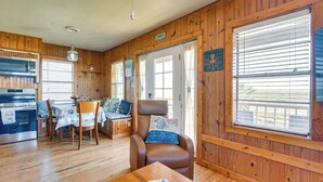 A wooden interior with a dining area, a kitchen, and a seating area with a chair and table. - Waterfront Texas Abode w/ Boat Ramp, Pets Welcome (Bay City)