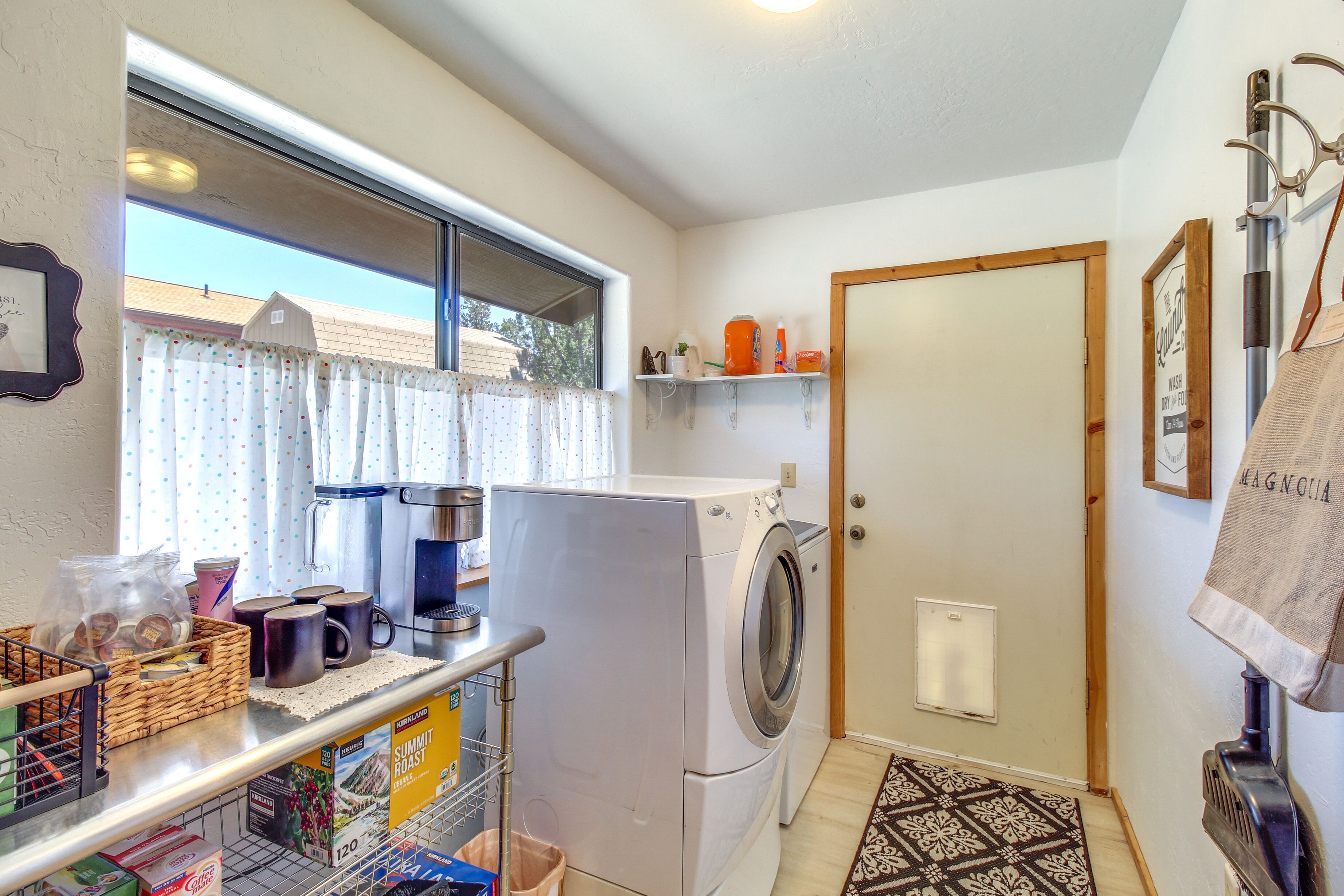 A laundry area with a washing machine, a coffee maker, and a basket of laundry supplies.