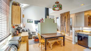 Eine moderne Küche mit Essbereich, Holzschränken, einem eingebauten Backofen und einer Pendelleuchte.
