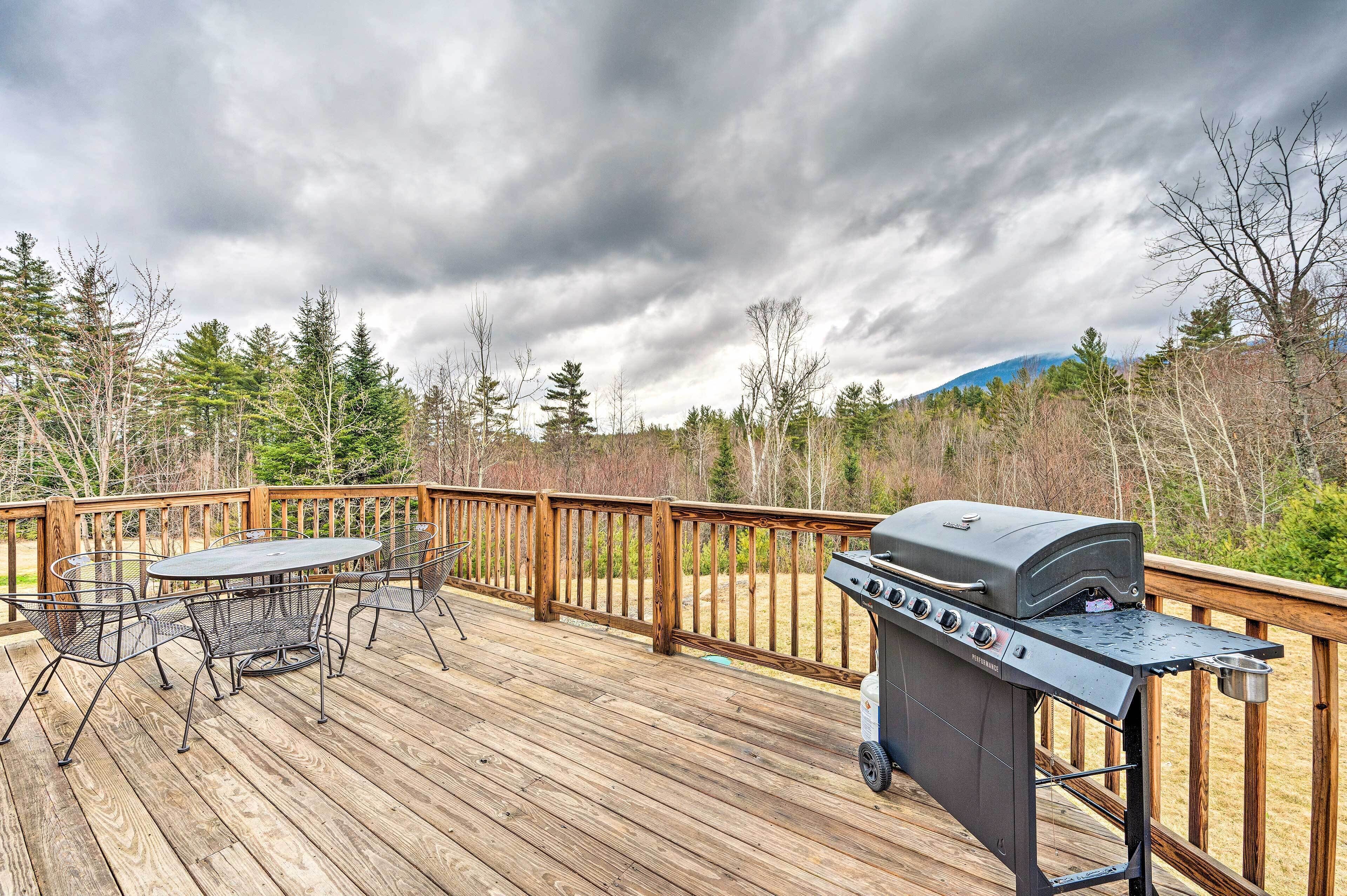 A wooden deck with a grill and outdoor seating.