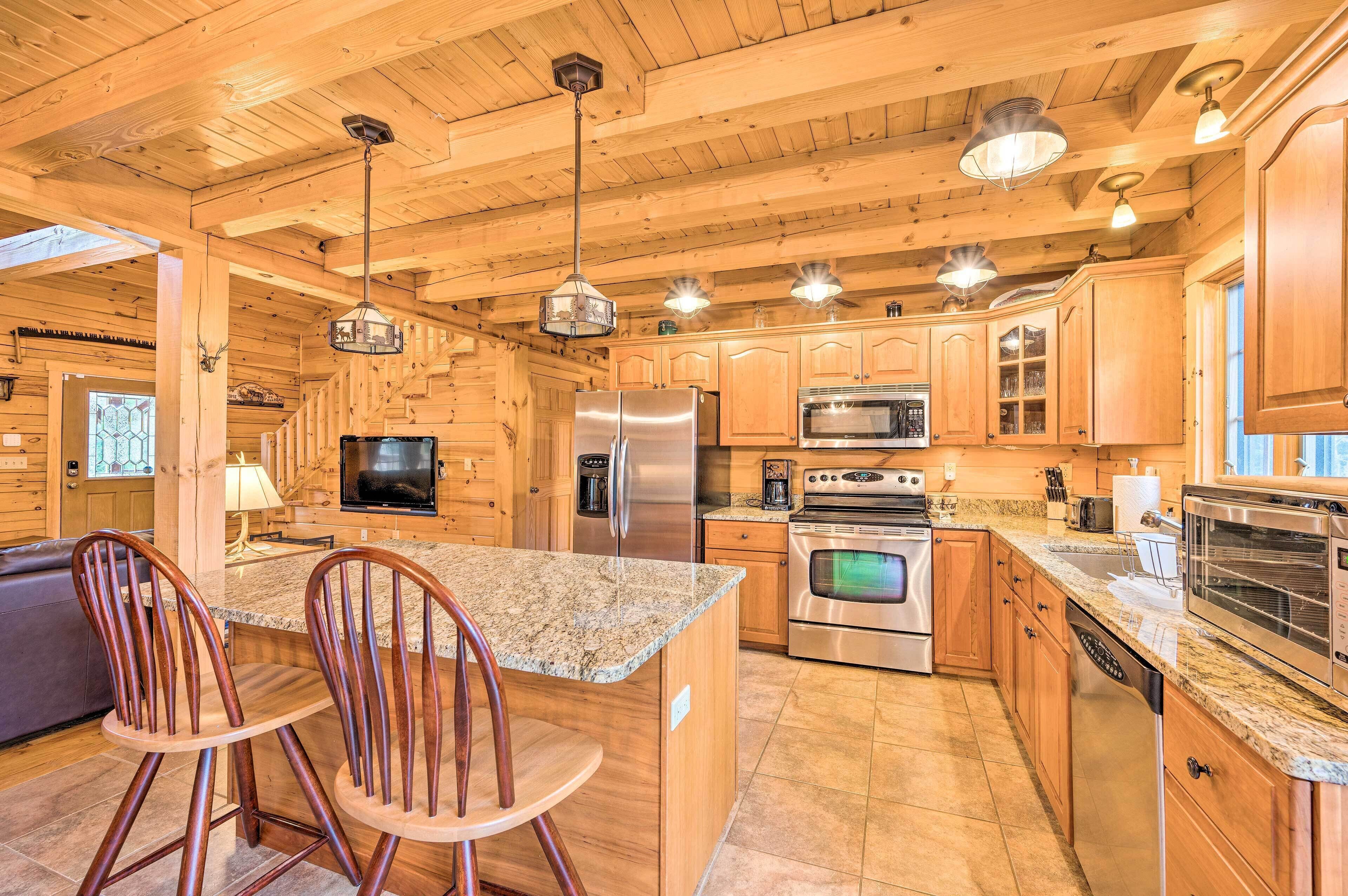 A spacious kitchen with wooden cabinets, granite countertops, stainless steel appliances, and a central island with bar stools.