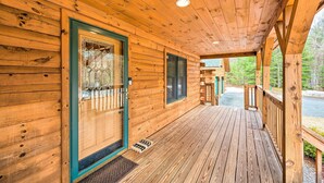 Een houten chalet met een overdekte veranda, een deur met ruitpanelen en een klein raam.