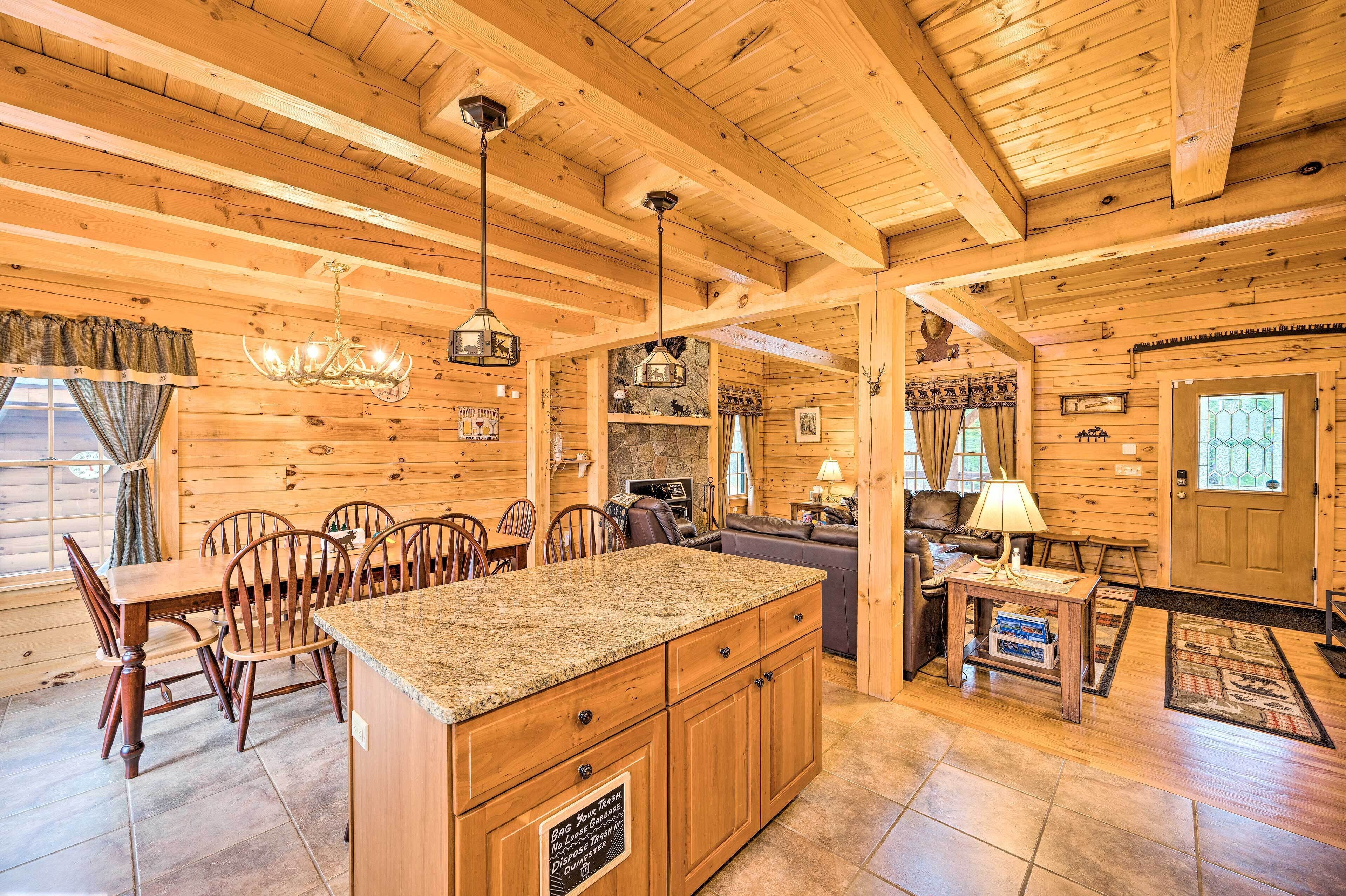 A log cabin interior with a kitchen, dining area, and living room.