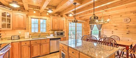 Una cocina de estilo cabaña de madera con encimeras de granito, armarios de madera y una isla central.
