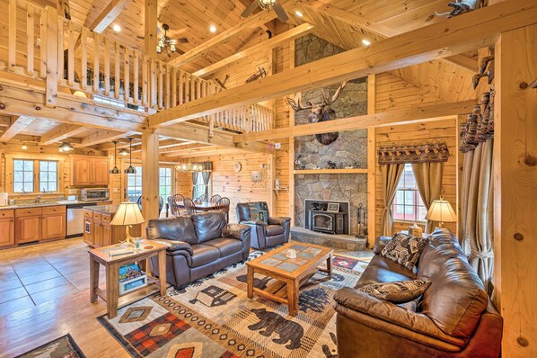 A spacious living area with a fireplace, leather sofas, and a stone wall.
