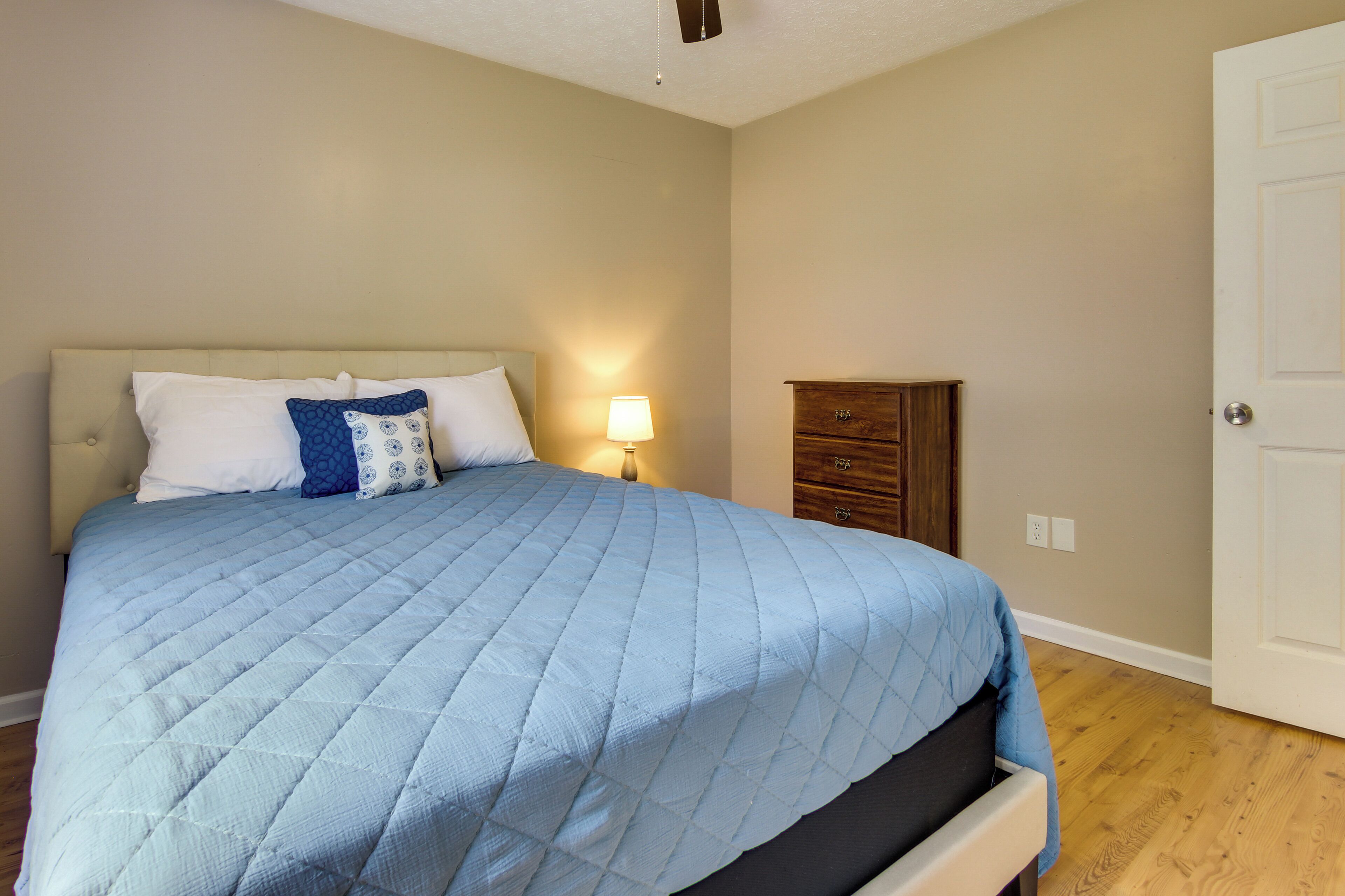 Un dormitorio con cama, mesita de noche, cómoda y puerta.