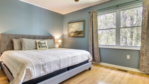 A bedroom with a bed, a ceiling fan, a window with curtains, and a painting on the wall. - Pet-friendly Black Mountain Vacation Home w/ Deck (Black Mountain)