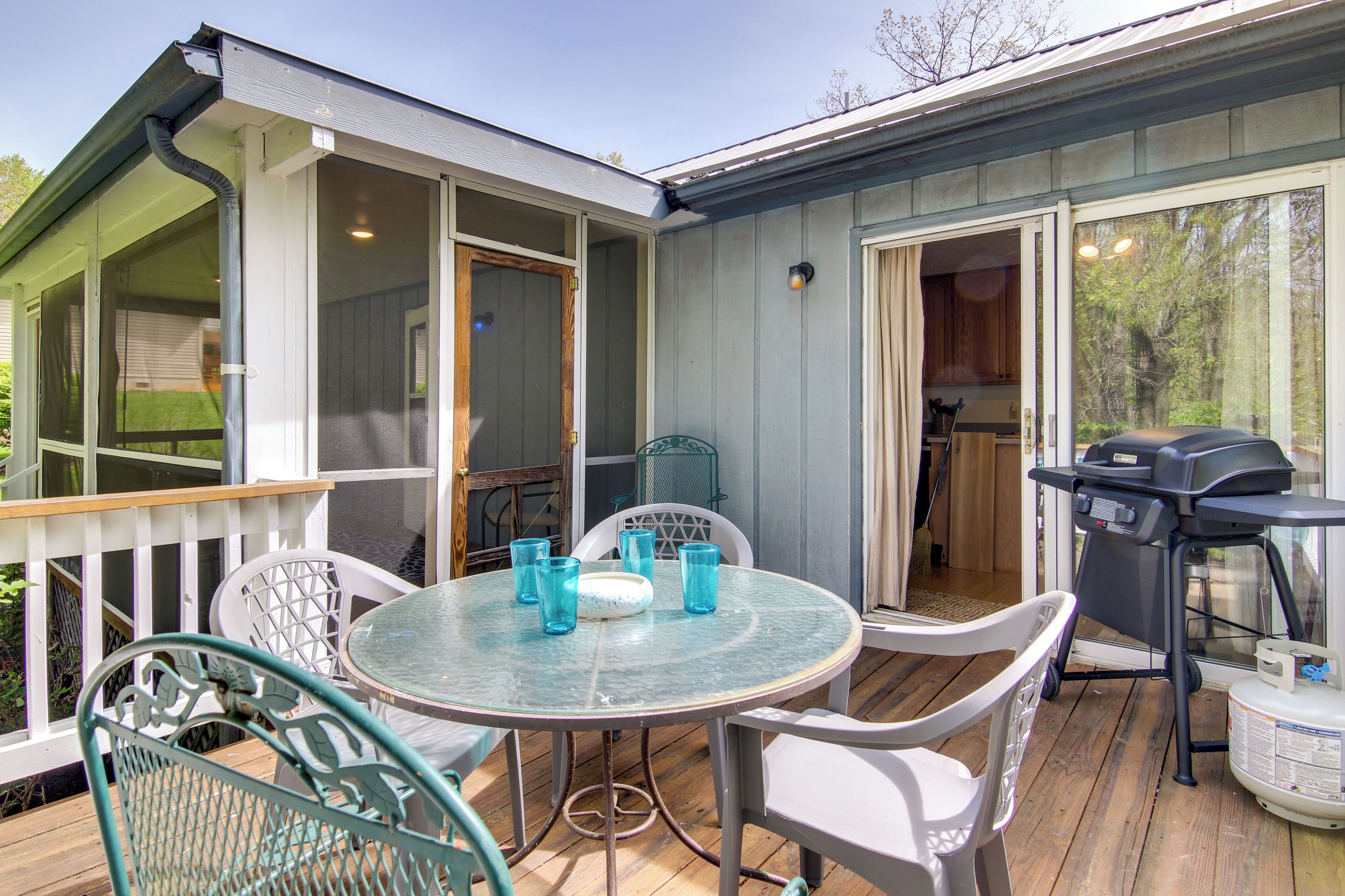 A covered outdoor patio with a round table and chairs, a grill, and a view of the surrounding area.