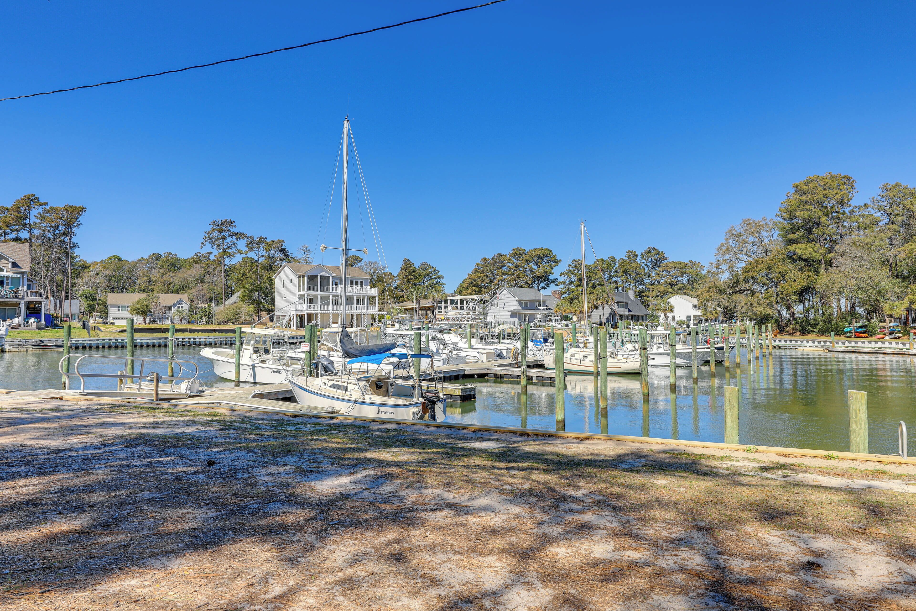 A marina with boats docked, surrounded by trees and a clear blue sky.