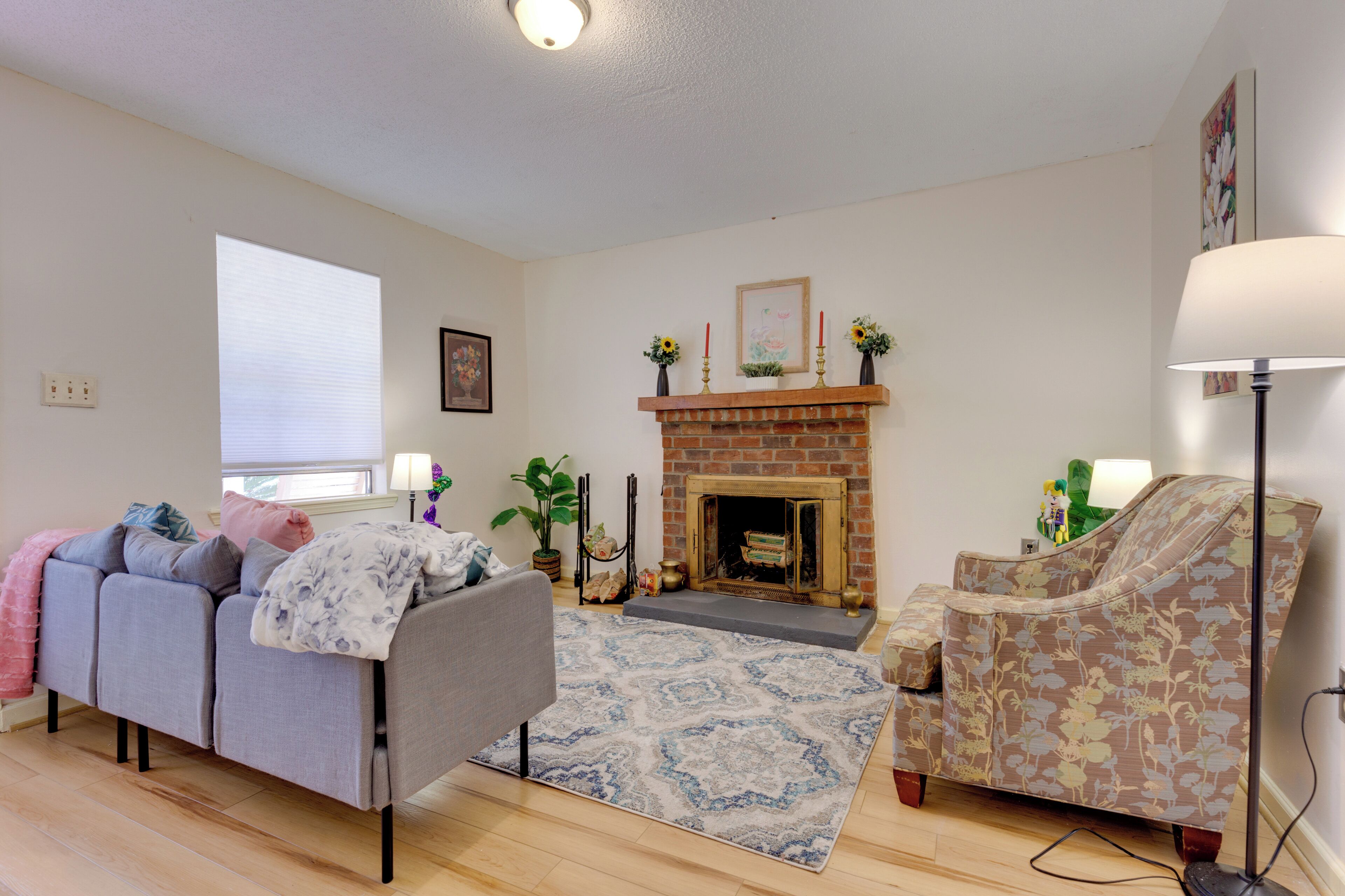 A living room with a fireplace, a sofa, a chair, and a floor lamp.