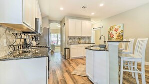 A modern kitchen with white cabinets, a marble countertop, and a wooden floor. - Pet-friendly Home w/ Pool, 25 Mi to Austin! (Leander)