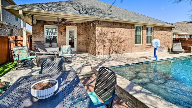 A backyard with a swimming pool, patio furniture, and a brick house. - Pet-friendly Home w/ Pool, 25 Mi to Austin! (Leander)