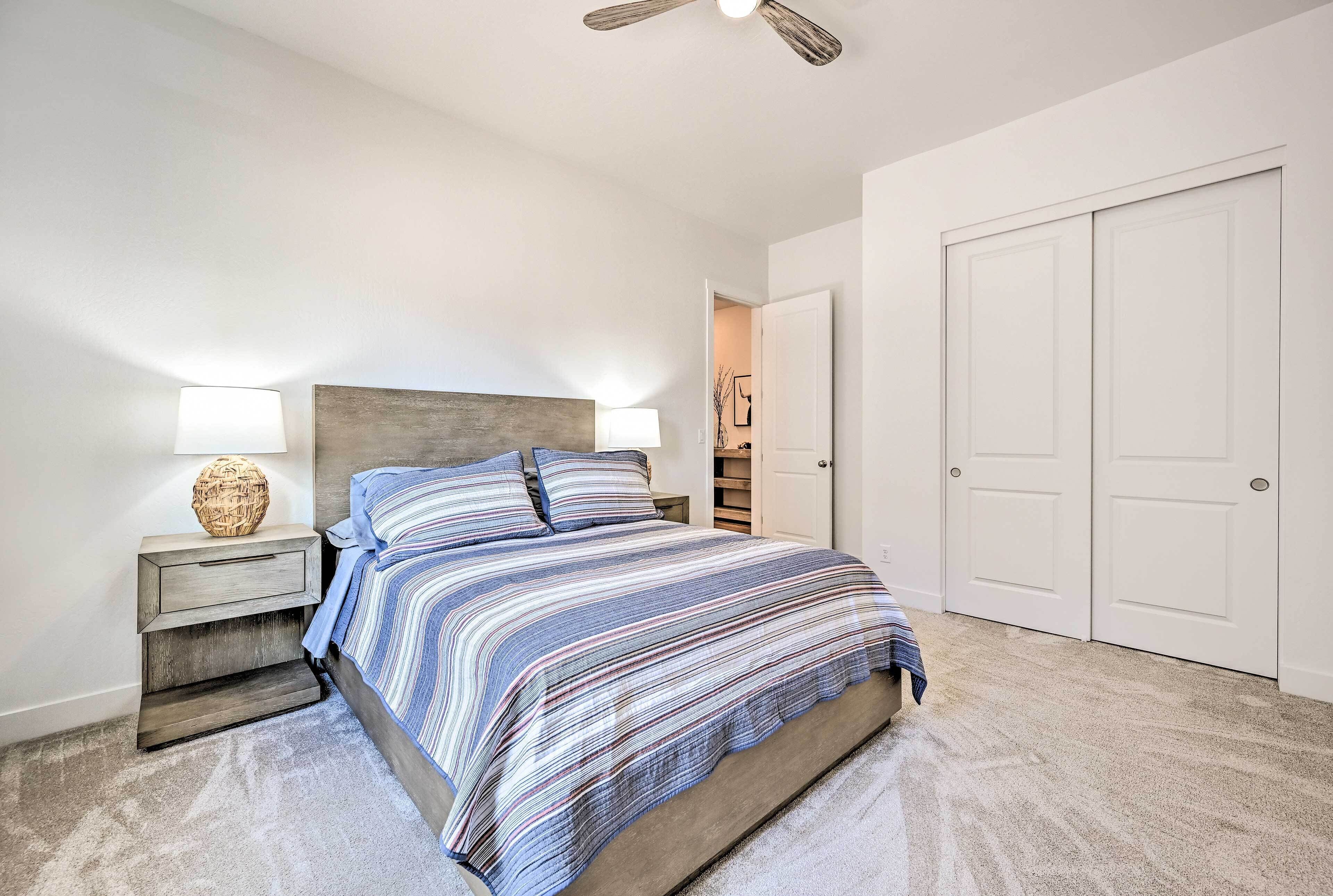 A bedroom with a bed, nightstands, a ceiling fan, and a closet.