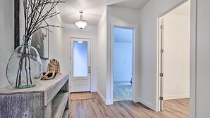 A hallway with wooden flooring, a glass vase with branches, and a framed picture on a console table. - Flagstaff Retreat w/ Covered Patio, 3 Mi to Dtwn (Flagstaff)