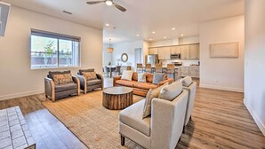 A spacious living room with a large window, a ceiling fan, and a kitchen in the background. - Flagstaff Retreat w/ Covered Patio, 3 Mi to Dtwn (Flagstaff)