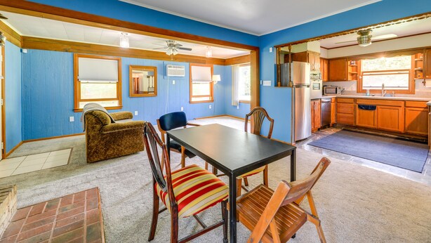 A dining area with a table, chairs, and a sofa. There is a kitchen area with cabinets and appliances visible through an open doorway. - North Carolina Getaway Near Kayaking & Fishing! (Oriental)