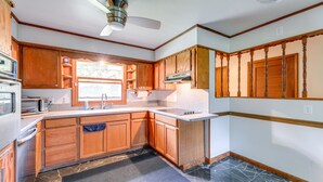 A kitchen with wooden cabinets, a microwave, a sink, and a ceiling fan. - North Carolina Getaway Near Kayaking & Fishing! (Oriental)