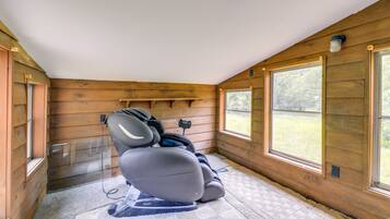 Ein Massagesessel in einem Holzraum mit großen Fenstern und einer Deckenleuchte.