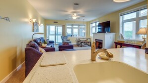 A modern kitchen with a large island, a dining area with a table and chairs, and a living room with a sofa and a TV.