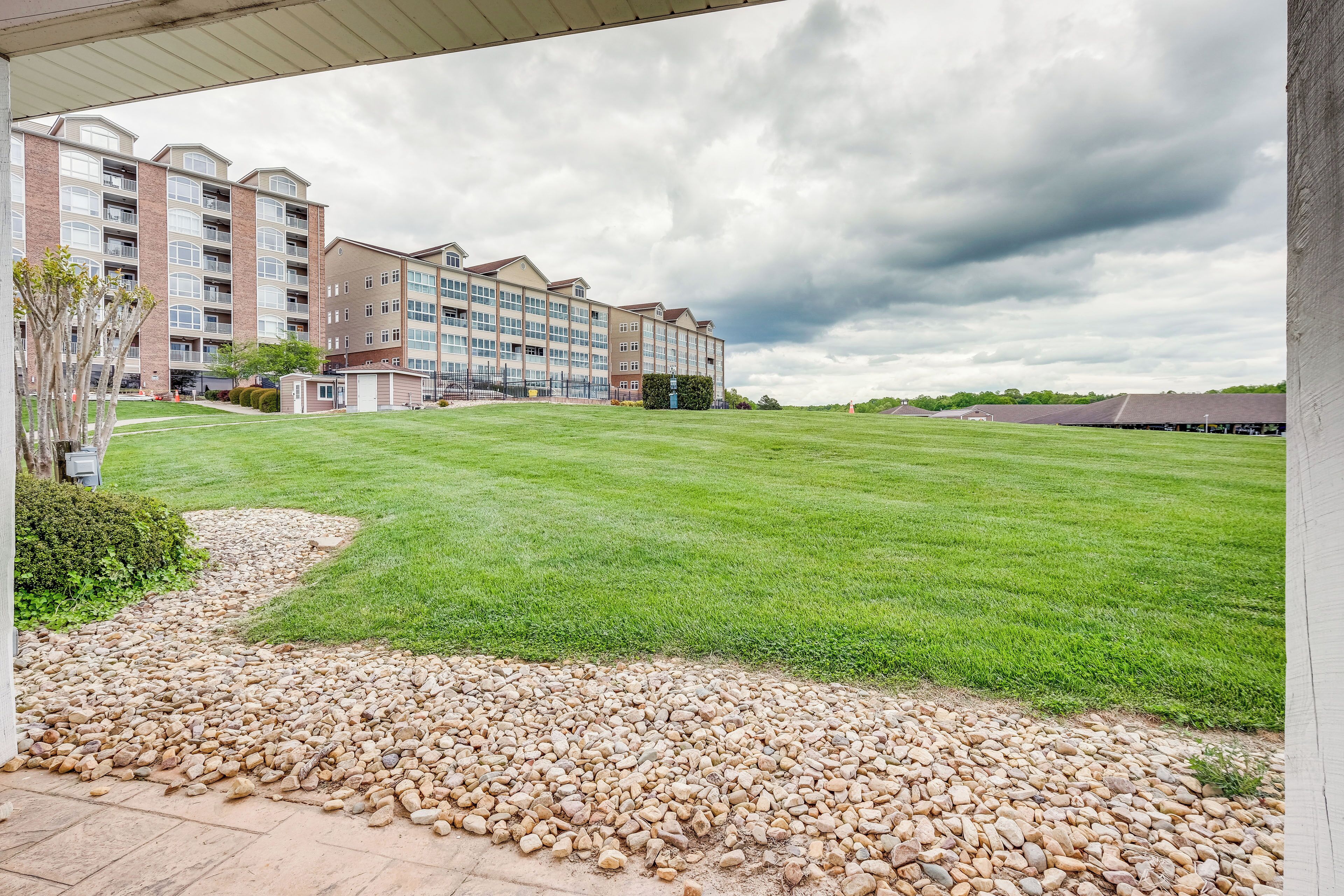 A hotel with a grassy lawn, a pathway of pebbles, and a brick building with multiple floors and balconies.