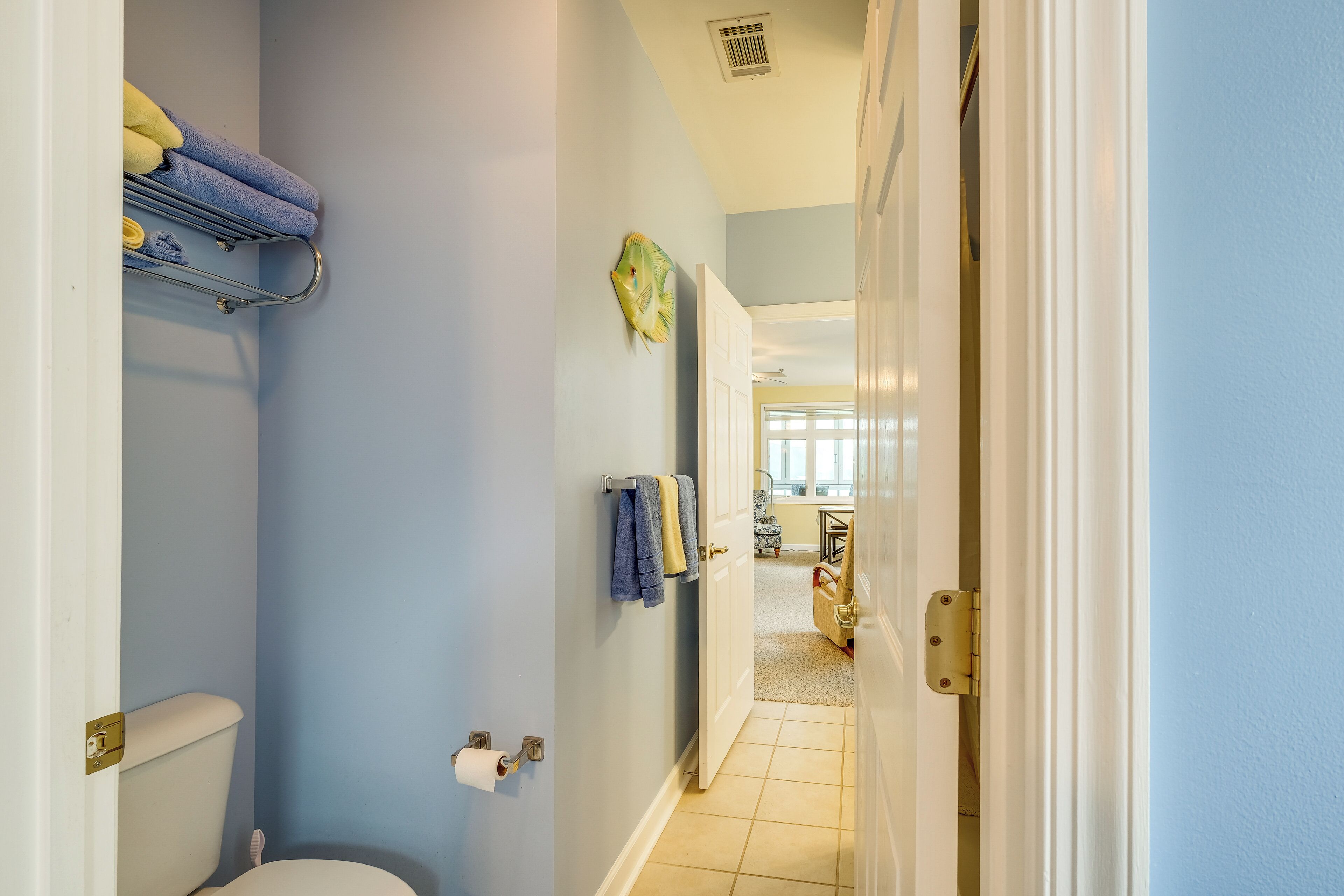 A bathroom with a toilet, towel rack, and a door leading to another room.
