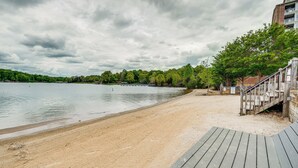 A beach with a wooden deck and a building in the background.