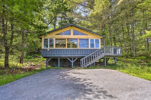 Une cabane dotée d’une terrasse en bois et d’un escalier menant à un porche abrité.