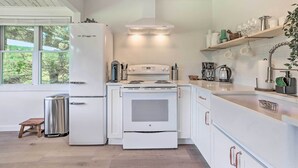 A modern kitchen with white cabinetry, a stainless steel refrigerator, a built-in oven, and a stove. There is a wooden stool and a trash can. - Catskills Sanctuary w/ Lake Access + Hot Tub (Narrowsburg)
