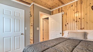 A bedroom with a wooden ceiling, a bed with a gray quilt, and white doors. - Cozy Elmira Cabin ~ 23 Mi to Boyne Mountain Resort (Mancelona)