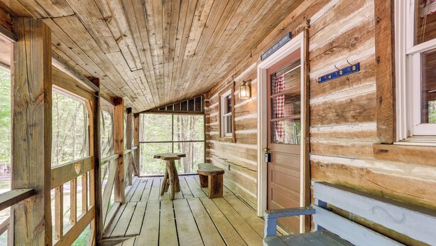 A wooden cabin with a porch, wooden walls, and a bench. - Historic Log Cabin w/ Porch Near Patoka Lake! (Taswell)