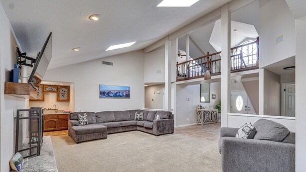 A spacious living area with a large sectional sofa, a smaller sofa, a staircase, and a kitchen in the background. - 3,000 Sq Ft & Large Yard! 5BR Lake Havasu Home (Lake Havasu City)
