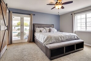 A bedroom with a bed, a ceiling fan, and a sliding glass door leading to an outdoor area.