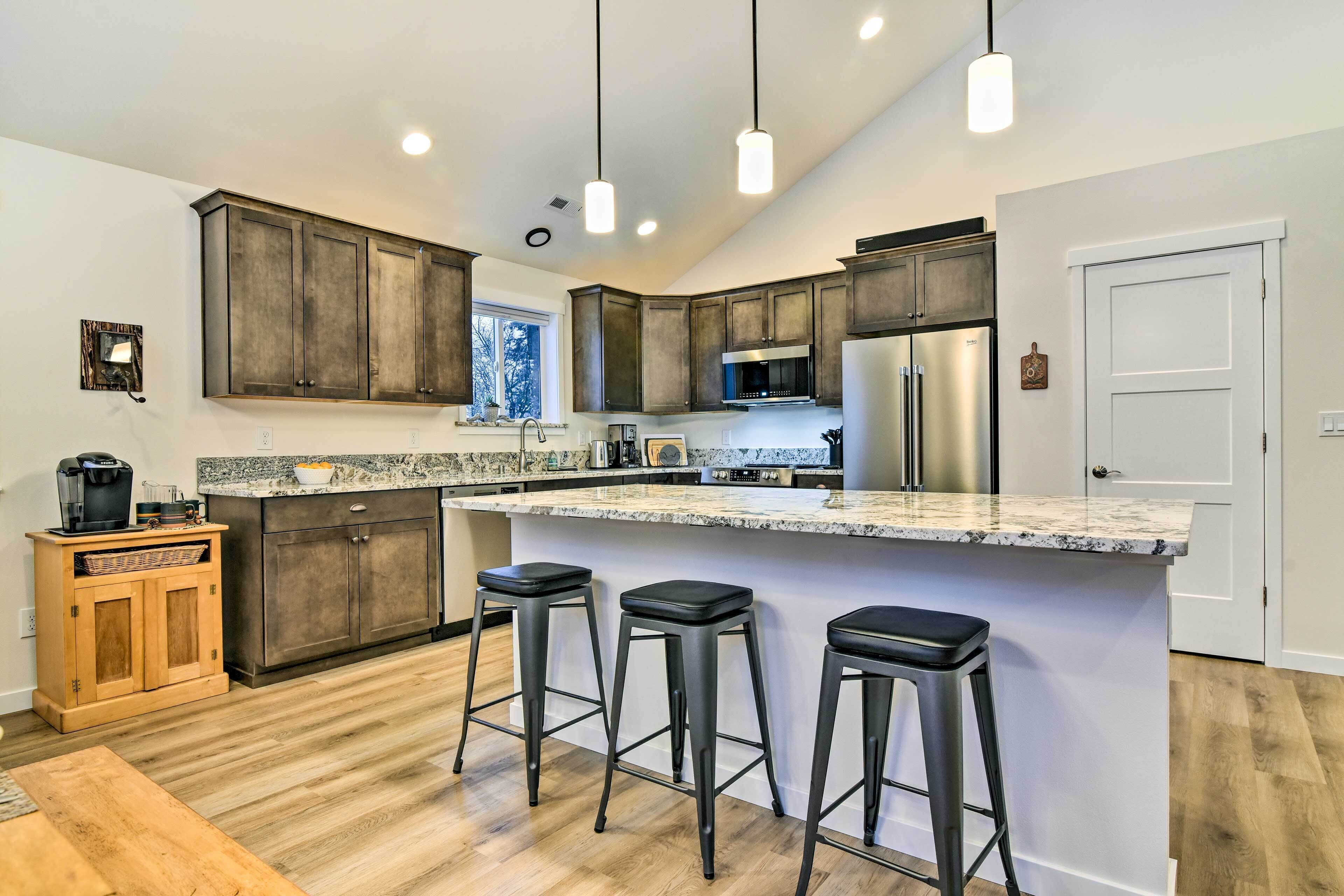 A modern kitchen with dark wood cabinets, a large island with bar stools, stainless steel appliances, and pendant lighting.